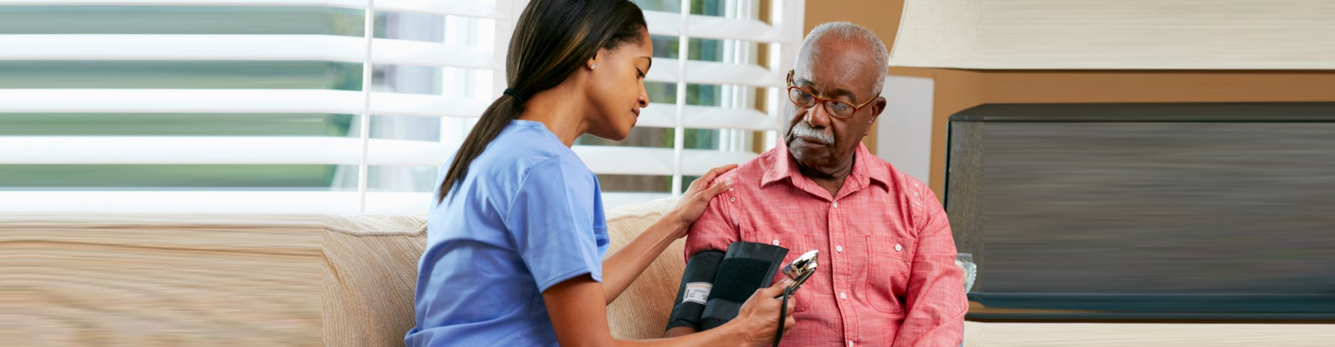 woman checking senior man's blood pressure